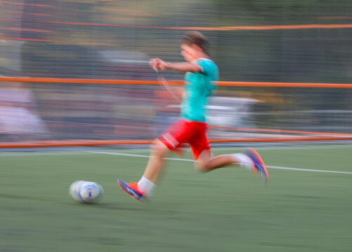  teen  boy  plays football at a sports school .Blur