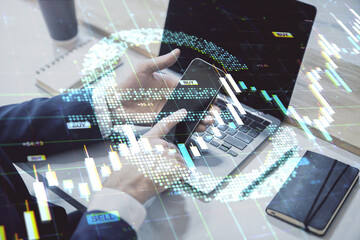 Businessman using smartphone and laptop with digital euro sign and financial graphs overlay in modern forex and stock market concept background.
