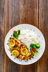 Lemon chicken escalopes with rice on wooden table
