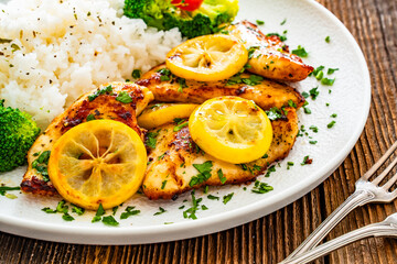 Lemon chicken escalopes with rice on wooden table