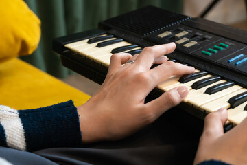 Woman musician playing a vintage synthesizer at home, crafting unique electronic music and fully...