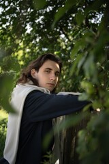 Young person leans against a rustic fence surrounded by vibrant greenery in a tranquil countryside...