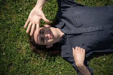 Relaxing under the sun, a young man enjoys a peaceful afternoon on the grassy field filled with sunshine and tranquility