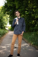 Young man poses confidently in a serene pathway surrounded by lush greenery during the late...