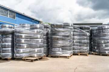 Plastic pipe rolls stacked on pallets for construction warehouse logistics and outdoor storage.