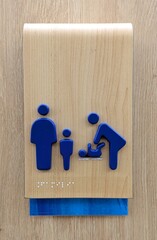 Letrero de sala para cambiar pañales en la pared de un centro comercial. Símbolo de madre y bebé con familia con escritura braille