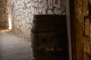 Old wooden wine barrel in a stone wine cellar, used for wine aging and storage in traditional...