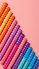 Obraz premium Colorful markers arranged diagonally on a pink background creating a vibrant and artistic composition