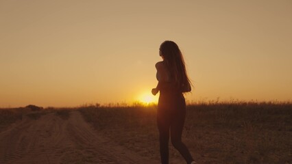 silhouette of sportive girl runs at sunset in sky outdoors, maintain healthy lifestyle with cardio workouts in sun, female fitness at dawn, morning endurance training against laziness, slow motion.