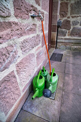 Plastic garden sprinklers standing against a stone wall. A country concept.