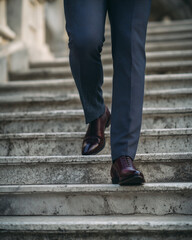 A man wearing a suit and blue pants is walking up a set of stairs