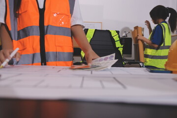 Closeup of team of industrial engineers meeting analyze machinery blueprints consult project on...