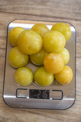 portion control: fresh mirabelle plums on a kitchen scale