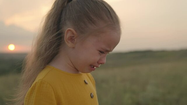 a little upset child is crying at sunset, tears are flowing down the kid's face, an expression of discontent emotion, cry of stress from the soul, girl does not want to obey, child problem of wet face