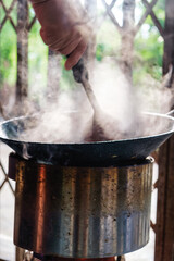 Hand stir frying in hot pan with smoky from traditional stove