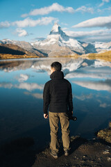 Man standing with camera at Lake Stellisee with Matterhorn mountain in Switzerland