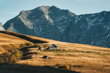 Rustic hut on dry hill with rocky mountain in autumn at French Alps