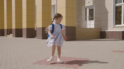 Little child with school backpack having fun spin in school yard, happy dreamy kid, first grader...