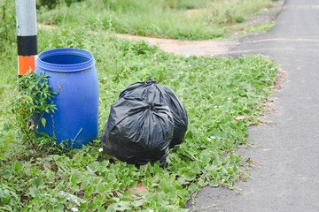 Close-up of a black bag next to a blue trash can.