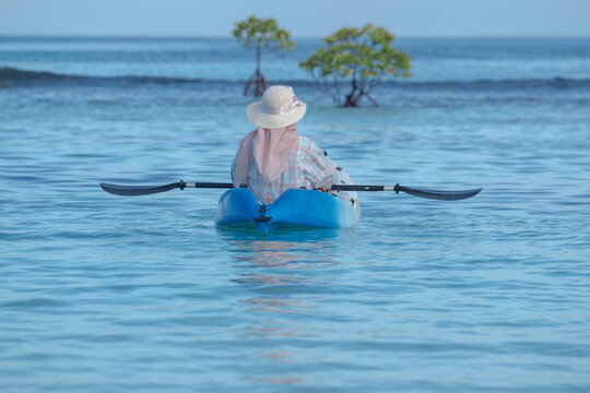 A young woman paddles a kayak on a tropical island. Slow motion video of a woman enjoying a sunny day while kayaking