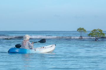 A young woman paddles a kayak on a tropical island. Slow motion video of a woman enjoying a sunny day while kayaking