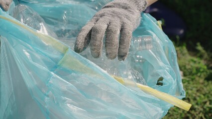 hand puts a plastic bottle in a bag, garbage for processing, eco, keep the environment clean, green...