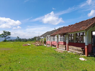 The school building and roof was damaged. School building needs immediate repair. Buildings with bright green and white clouds in the background
