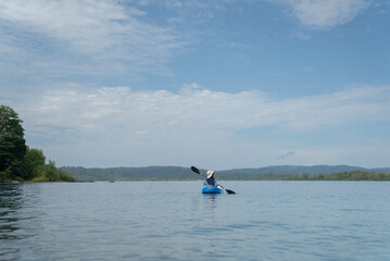 A young woman paddles a kayak on a tropical island. Slow motion video of a woman enjoying a sunny day while kayaking