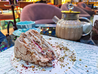 Close-up of an exquisite multi-layered cake with pistachio nuts and cream, a perfect sweet treat in a fancy restaurant setting.