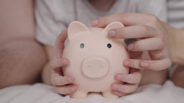 budget of a happy family, a hold on the future of life, a family security pillow, a pig piggy bank collects money, father and mother give cash a child, the concept of a child's dream of saving coins.