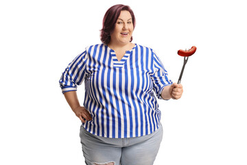 Corpulent woman holding a sausage with a big fork