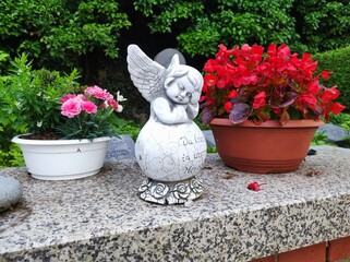 Engel mit Blumen auf Friedhofsmauer