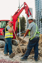 Construction workers repairing city infrastructure with heavy equipment and red polypropylene pipes. Urban utility maintenance, excavation, and roadwork in progress