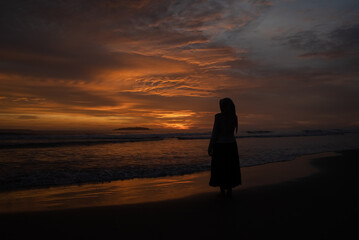 Fototapeta premium A woman enjoys the view of the beach at sunset
