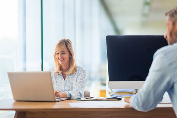 Group of business people sitting at office desk and using laptop and computer for work