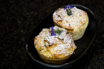 Rosemary flavoured muffins, decorated with a dusting of icing sugar and purple rosemary flowers.