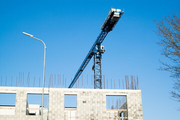 Unfinished construction of an apartment building made of gray blocks, blue sky and a high-rise...