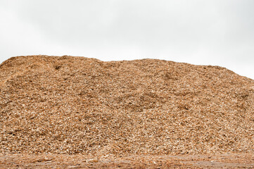 pile of wood chips against a gray sky close-up