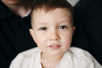 Close-up portrait of a cute little boy looking at camera, indoor natural light setting.