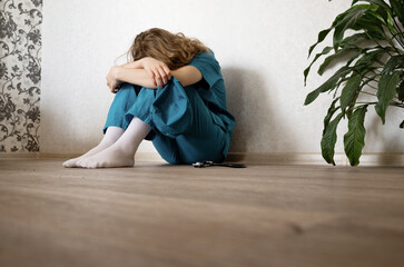 Healthcare worker in distress sitting alone on the floor in a quiet room