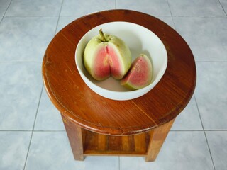 Red-fleshed guava is placed in a cup on a chair.