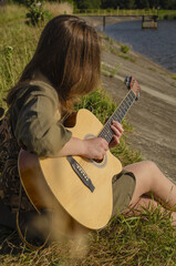 A girl with a guitar in cowboy style. Cowboy hat and boots. Sunny atmospheric photos.