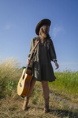 A girl with a guitar in cowboy style. Cowboy hat and boots. Sunny atmospheric photos.