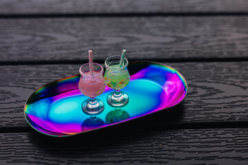 Two refreshing cool and funky cocktails with straws on a colorful, reflective tray. Summer...