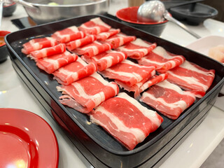 Raw sliced beef arranged on black serving tray