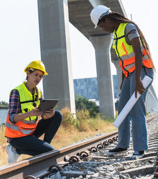 Diversity female locomotive engineers working outdoor at train track, rail technician women inspecting train track