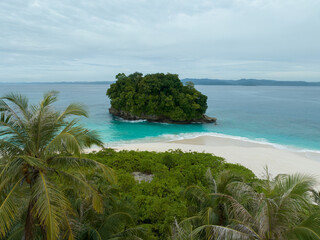 Fototapeta premium An aerial view of a tropical island with white sand beaches and turquoise waters. Waves crashing on a white sandy tropical beach