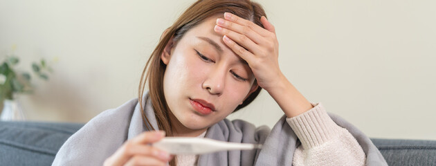 Female sick woman checking her body temperature have a high fever feeling headache.
