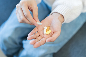 Close-up hands of person holding painkiller pills and vitamin