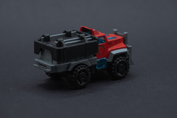 Toy fire truck on black surface suitable for childrens book illustrations, website graphics, firefighterthemed designs, educational materials. Playful and colorful.